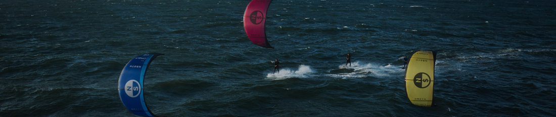 Kitesurfistas navegando con kites de colores al atardecer en Colombia